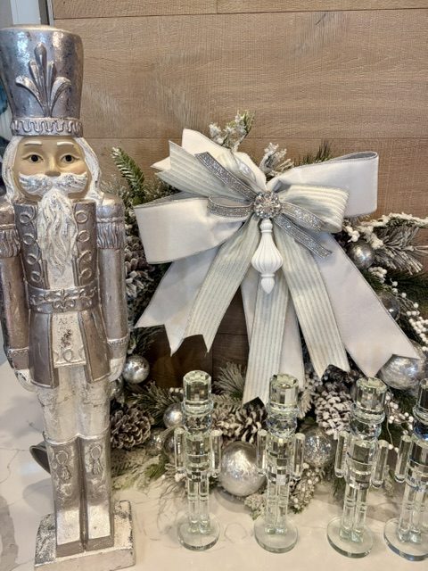Elegant silver and white custom holiday bow displayed with silver nutcrackers